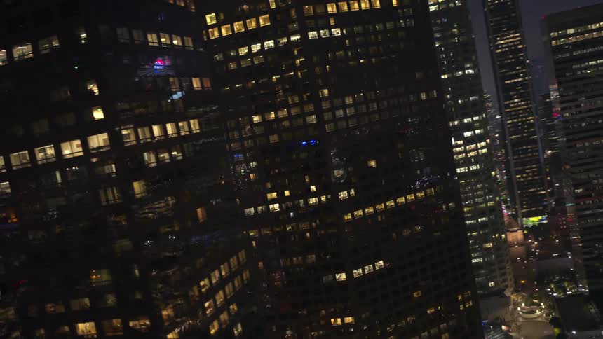 Skyscrapers tower above the other buildings in a dense city skyline at night