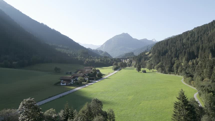 Aerial panorama of houses in a countryside surrounded by mountains and forests