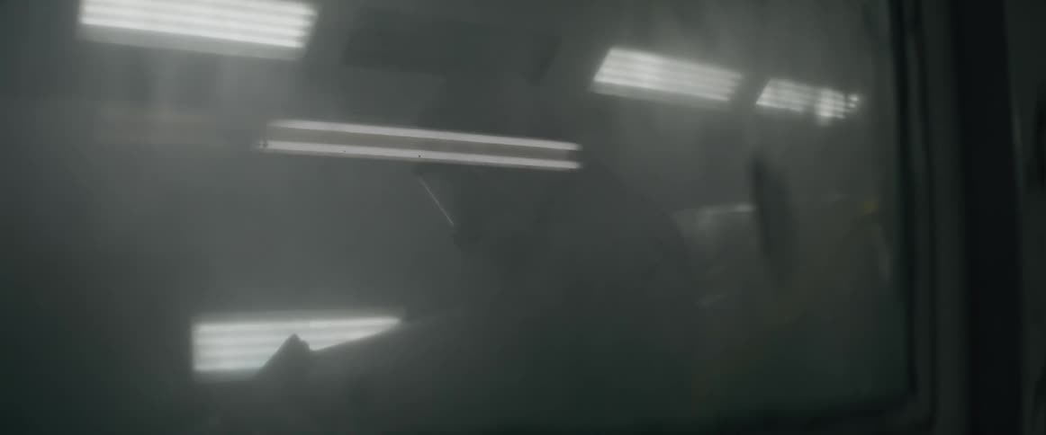 Two people inside a building seen reflected in dirty glass