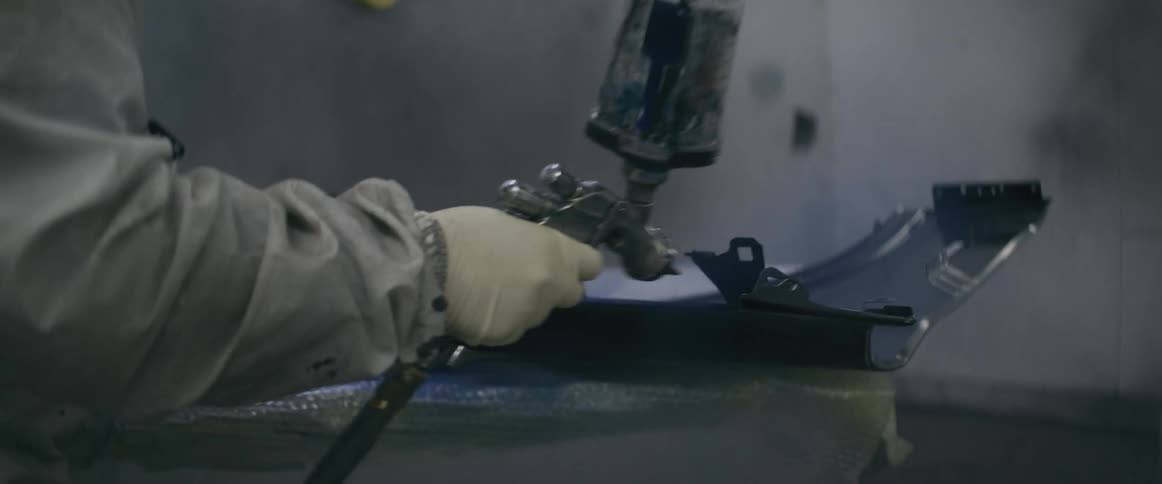 Person with glove and a tool painting a metal