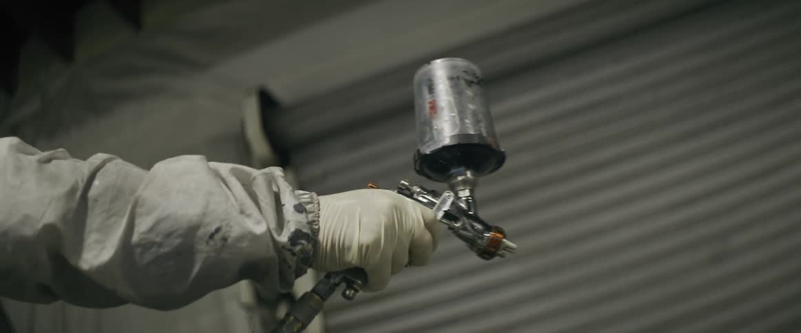 A worker sprays paint out of a spray gun