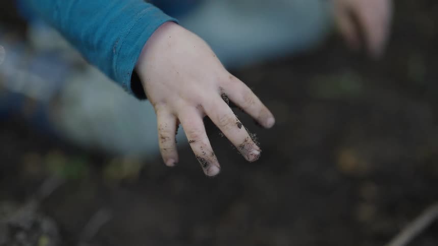 Close up of a childs hand playing with dirt