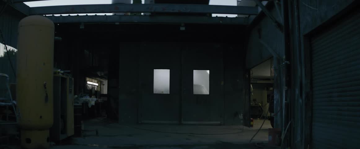 A dimly lit industrial space with a large metal door and a roll up door