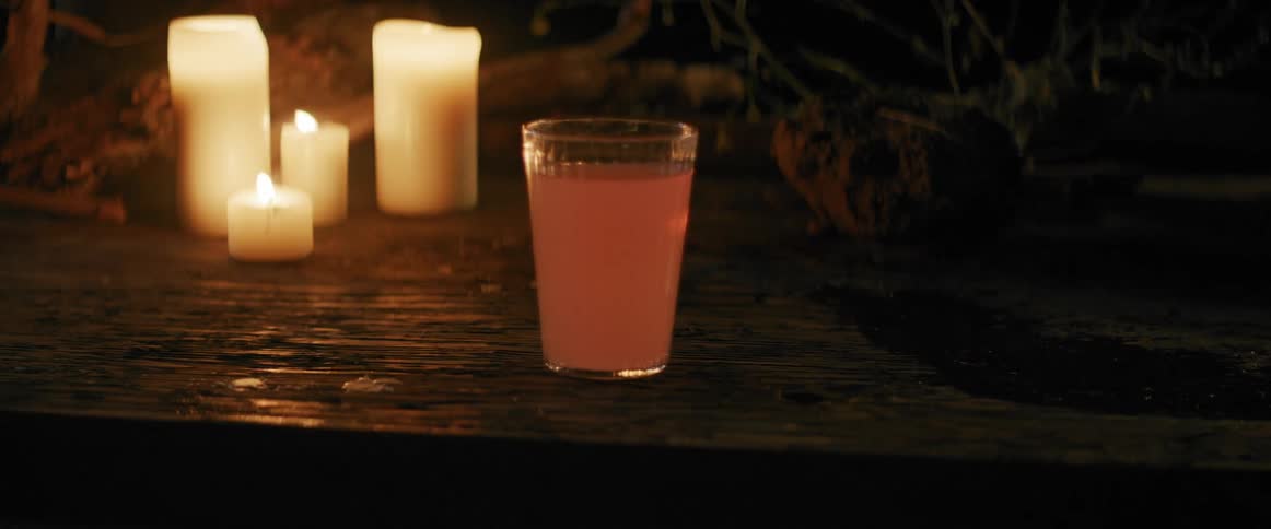 Glass filled with pink liquid on a candle lit table
