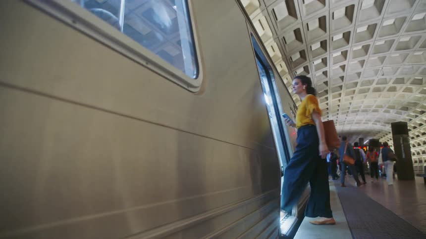 A young woman boards a subway train as other passengers get off