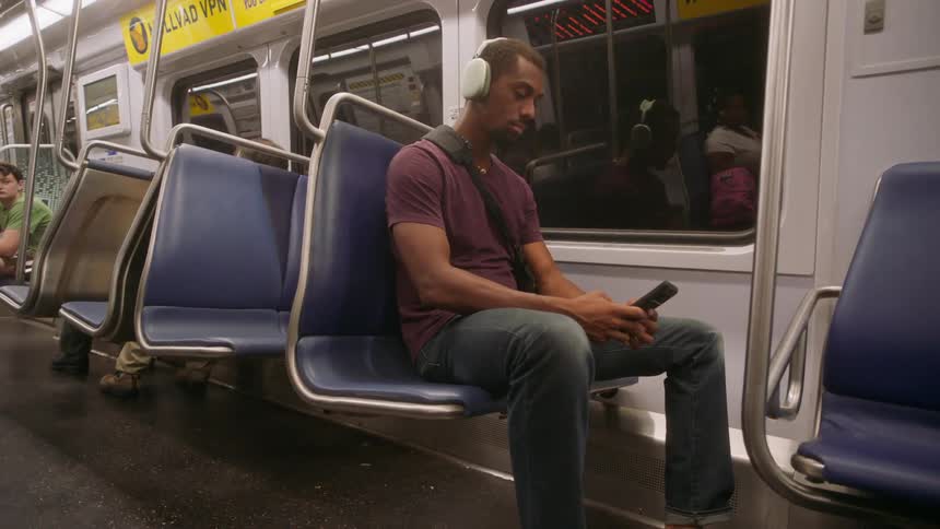 Man sitting on a moving train interacting with his cell phone