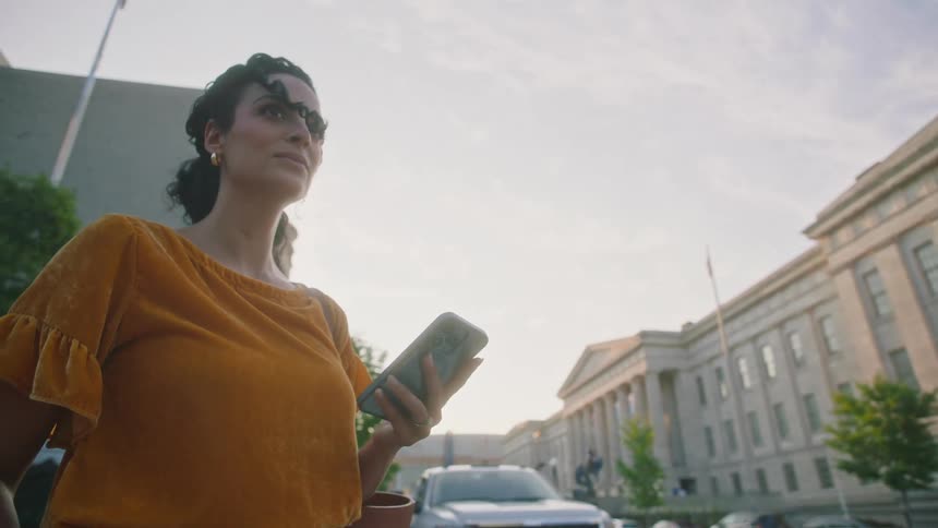 Woman in an urban city holding a smartphone and looking around