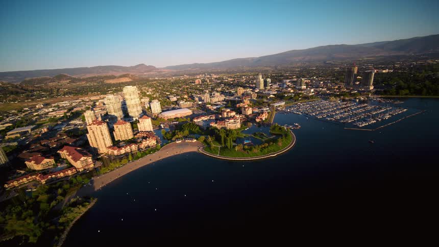 A city and large marina sits on a coast surrounded by mountain ranges