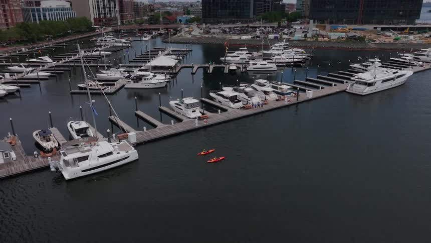 Two kayakers paddle past the marina at the edge of the city