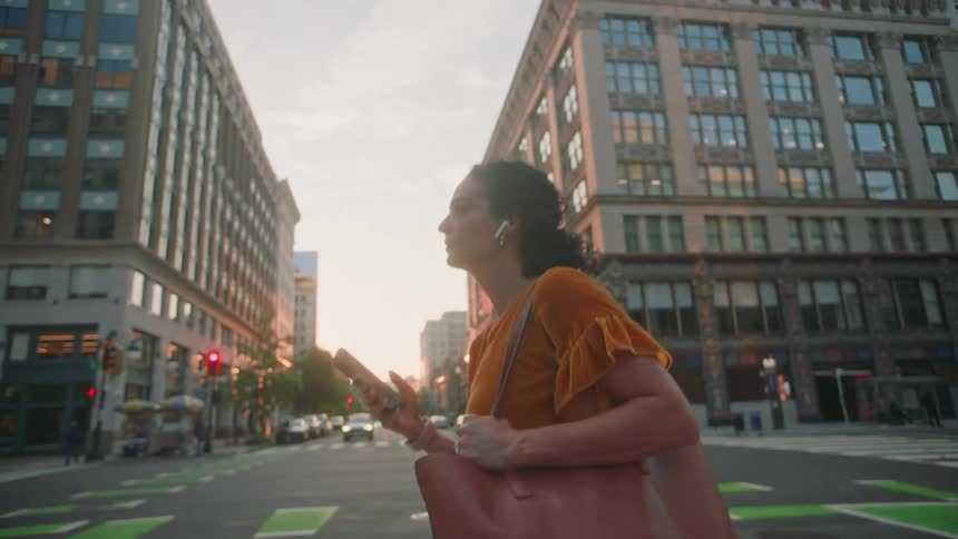 Woman crossing the street in a metropolis and interacting with a smartphone
