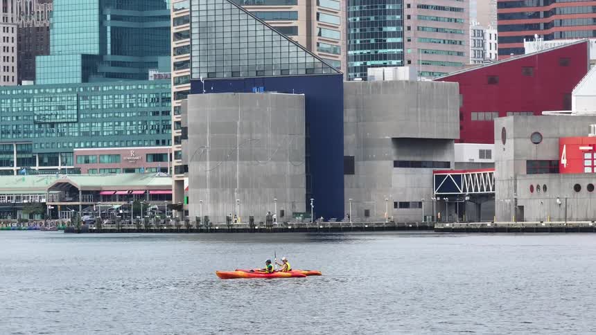 Two people are kayaking and kayaking in a canal near commercial buildings on the coast