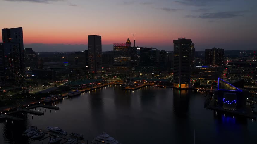 An aerial view of a metropolitan city with huge buildings facing a body of water at dusk