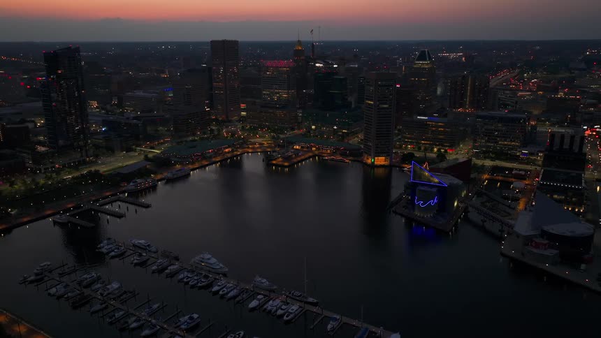 A large city with a marina sits on a coast at dusk