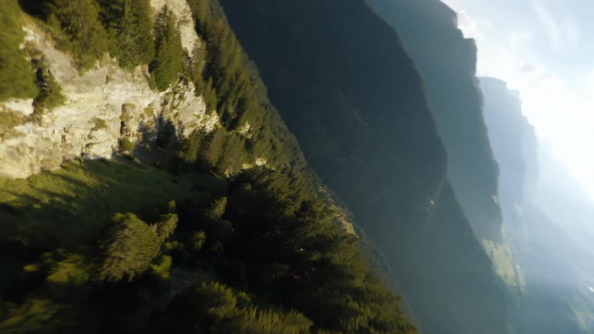 Sun shines through haze onto forest covered mountains