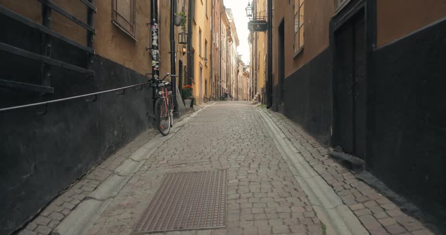 A cobblestone alleyway between yellow buildings in stockholm sweden