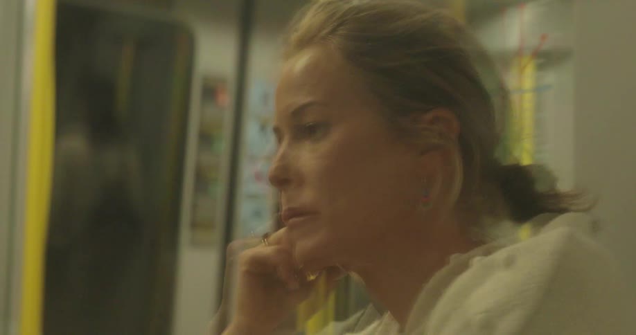 A  woman who looks sad rides on a train car