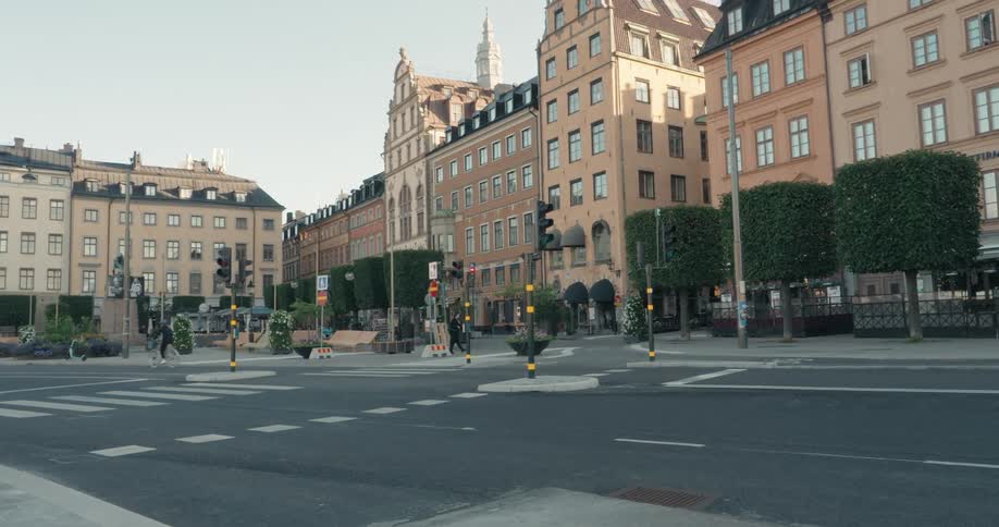 A large old beige building with several windows facing an asphalt street with a pedestrian and a bicycle passing by