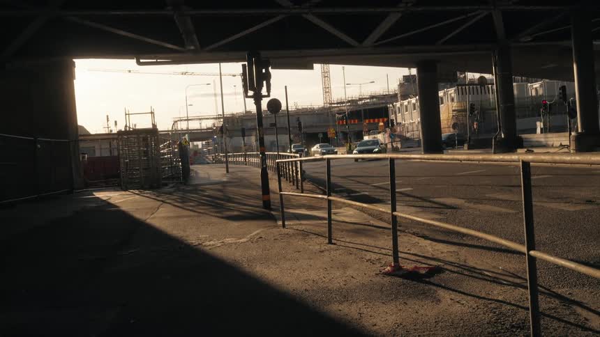 A train moves over an elevated track and cars turn on streets in a city