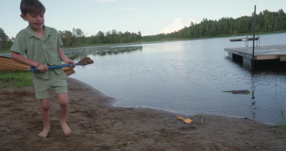 Boy holding a shovel and playing by the lake
