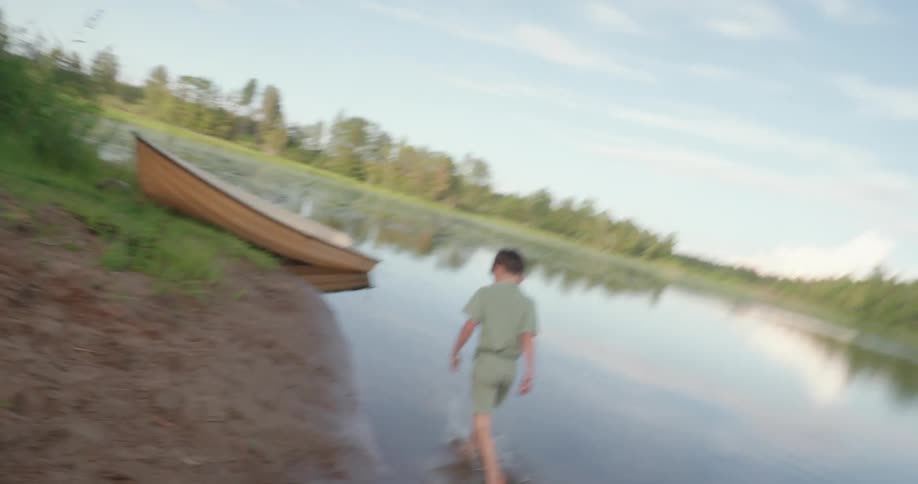 Boy running along the shore of a lake