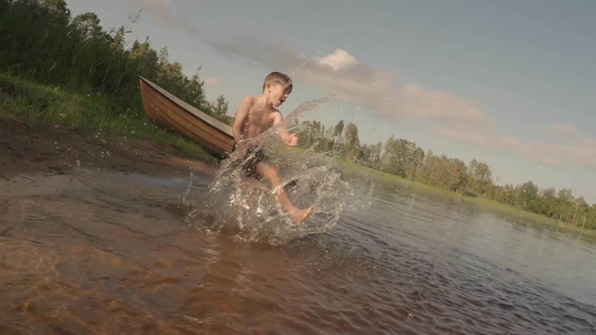 Little boy in a lake kicking the water