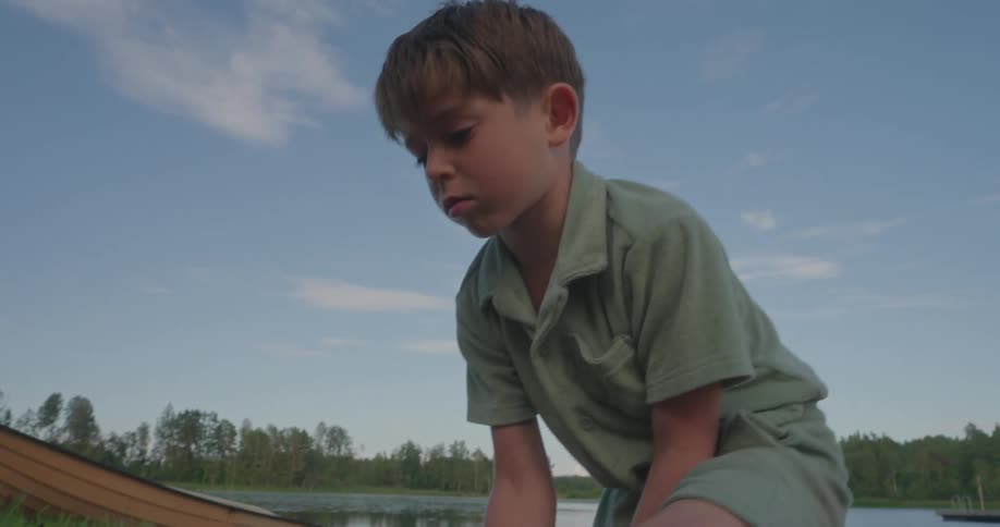 Boy with a shovel playing on the shore of a lake