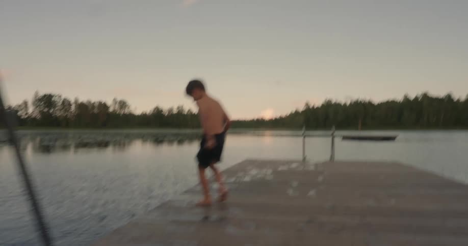 A child runs on the pier and jumps in the water