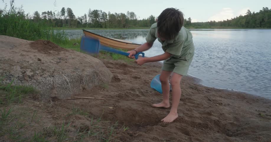 A young child pounds the ground with a shovel and then scoops dirt and moves it away from a hole