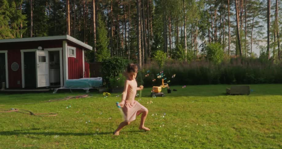 Boy in a backyard with a lawn playing with soap bubbles