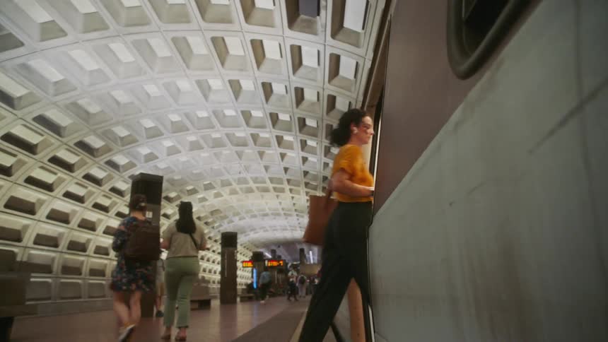 Several people enter and exit an underground train
