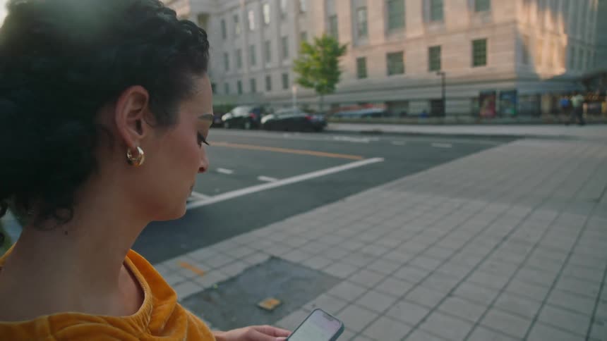 A woman checking her smart phone before crossing a six lane road