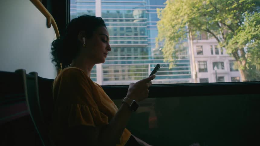 A woman is using her phone on the bus