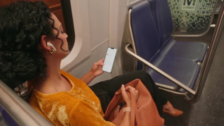 Woman sitting on a train bench and interacting with an iphone