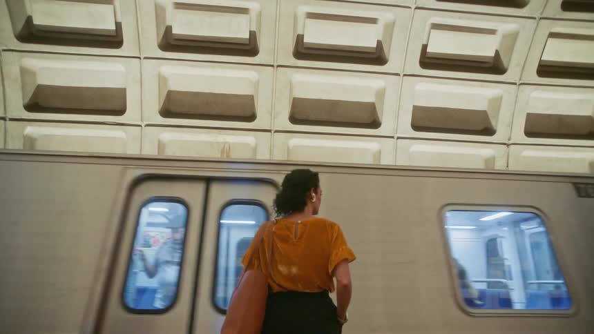 Waiting female passenger stands watching as subway train comes to a stop