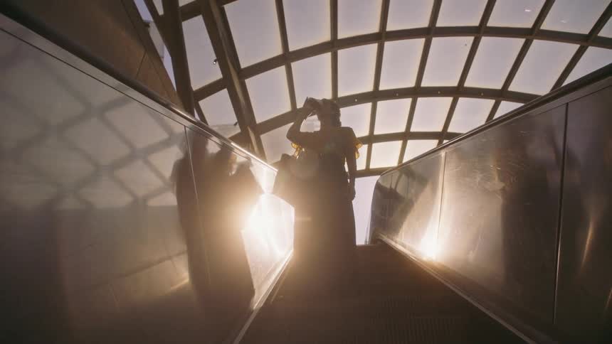 Woman having a drink and going down an escalator in a terminal