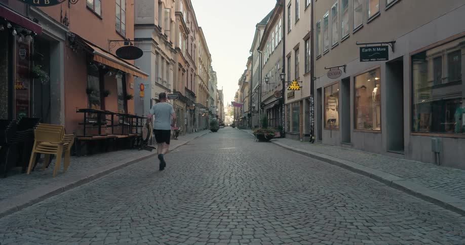 Man jogs along the cobblestone street between small shops