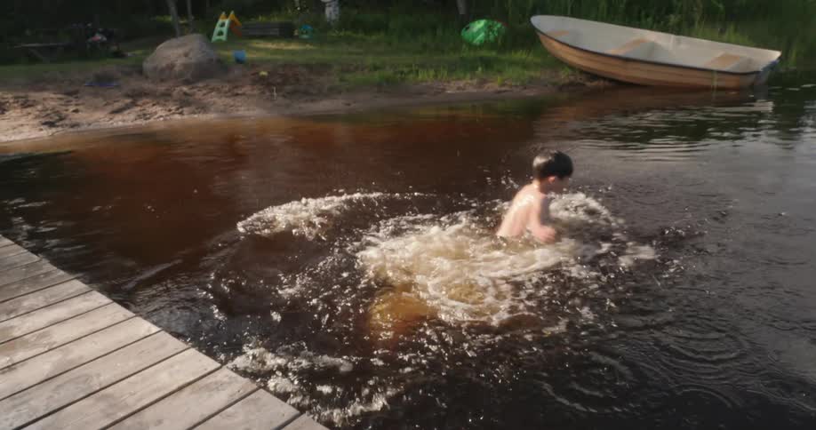 A child jumps off a wooden dock into a lake