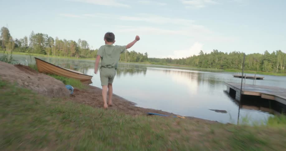 A child runs around by the lake