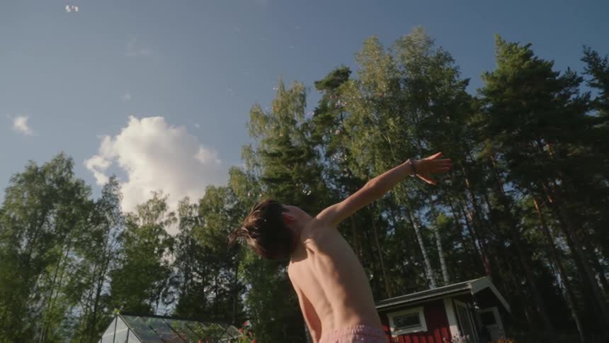A child jumps grabbing at bubbles
