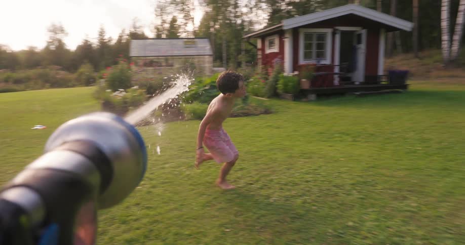 A child runs away from a yard sprinkler slips on the grass and gets soaked
