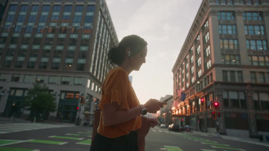 Woman crossing the street in a metropolis and using a smartphone