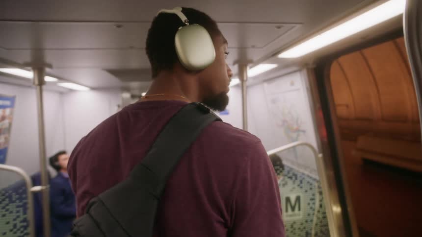 A man with headphones on walks out of a subway train
