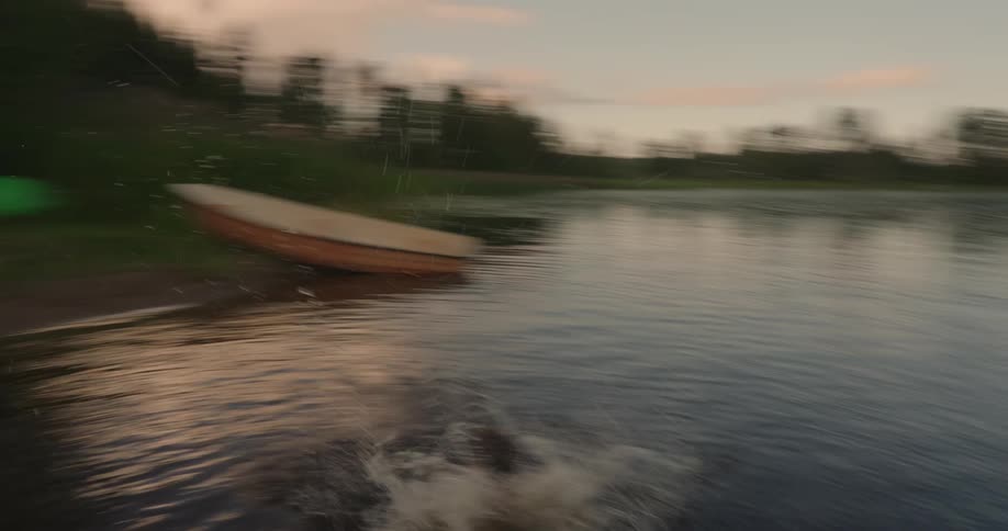Boy jumps off a dock into a pond after dusk