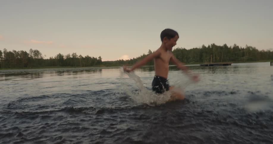 Boy playing in a lake splashing water