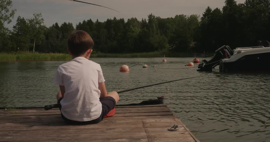 A young boy fishes off of a wooden dock
