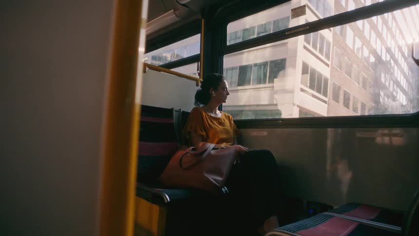 Female passenger sitting inside a bus looking out the window