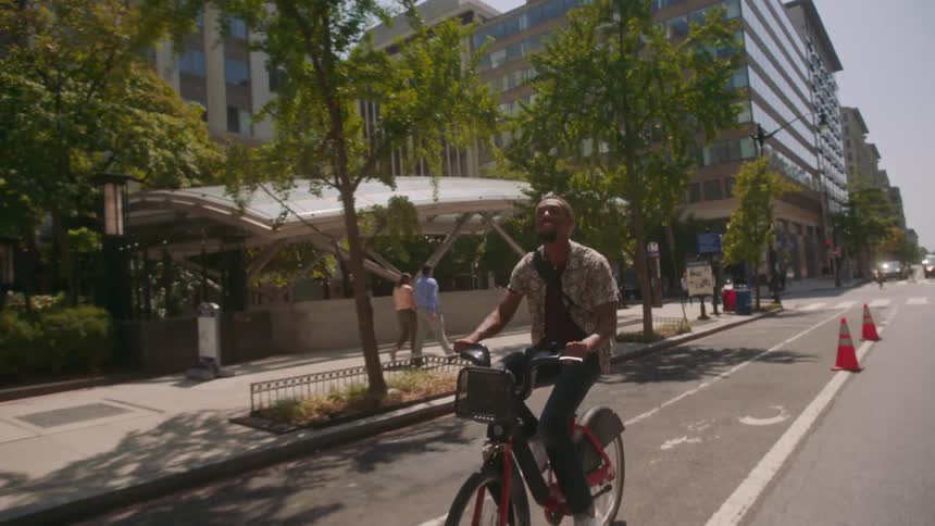 Man riding a bicycle on a bike path through a metropolis