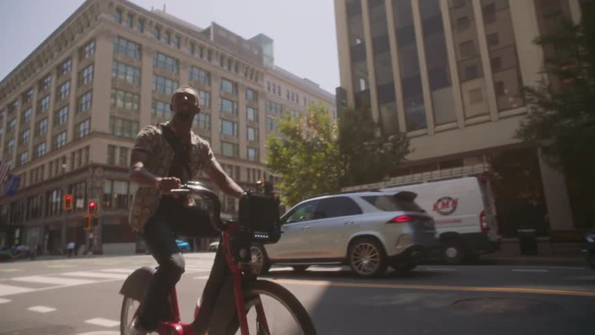 Man riding a bicycle through the streets of a metropolis during the day
