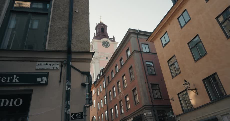 Narrow street with tall buildings featuring traditional european architecture leading to a prominent clock tower