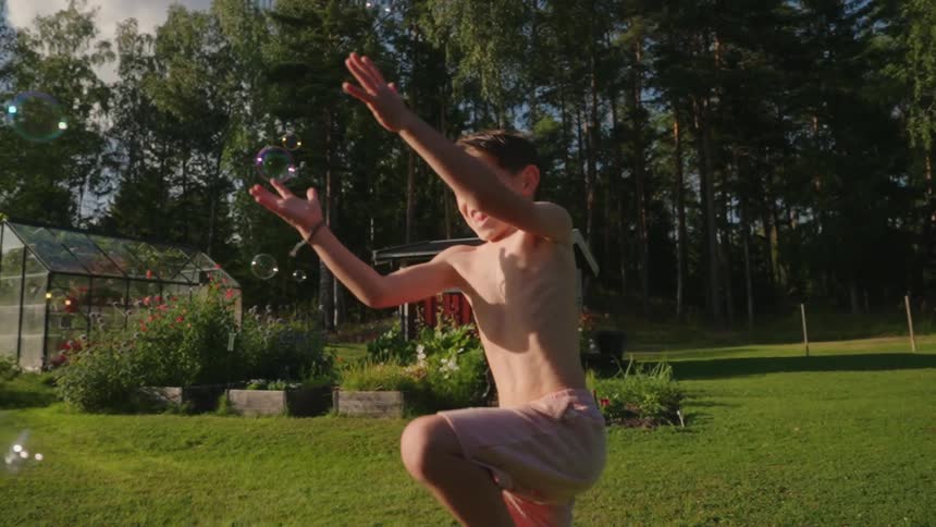 A child jumps and plays as bubbles float around